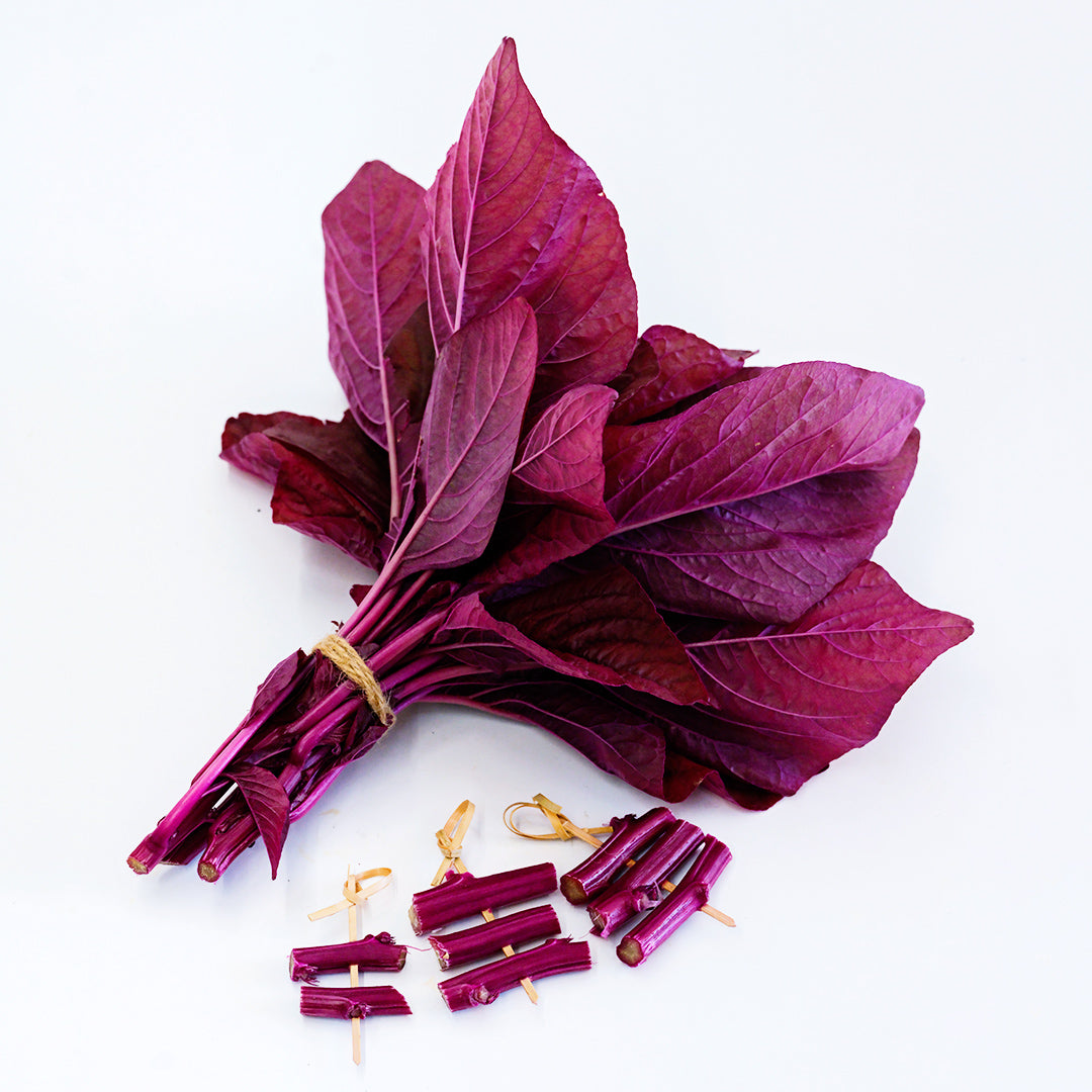 A bundle of Beetroot Vlathankara Amaranth with stems on toothpicks on a white background.