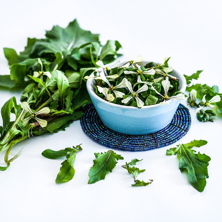 Neimatt's Battir Arugula salad in light blue bowl with flowers on a white background.