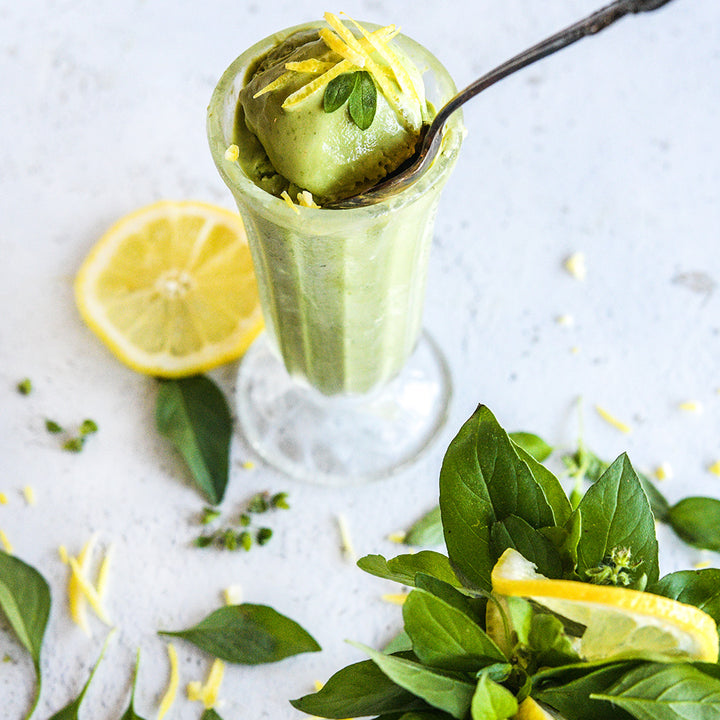 Lemon Basil ice cream with lemons and basil on a light background.