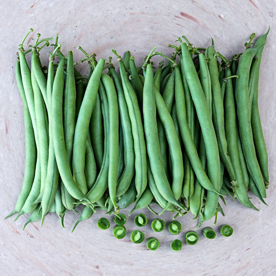 Whole and cut Cantare Beans in a pile on terra cotta pizza plate.