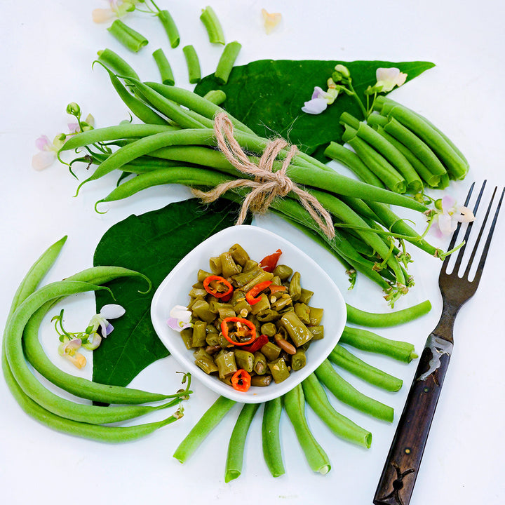 Whole and cut Calima Beans with pickled beans, blooms and foliage arranged on white background.
