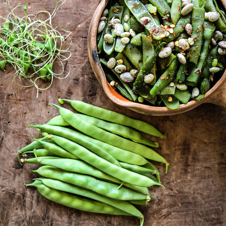 A close-up view of cooked and raw Greasy Grits Beans on a wooden background.