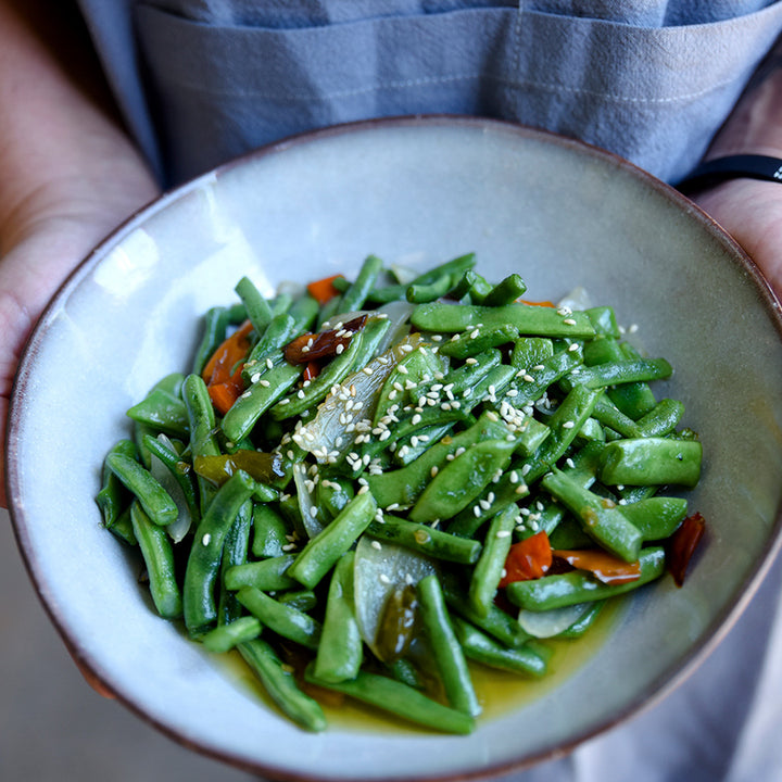 A woman holding a bowl of cooked McCaslan 42 Pole Beans.