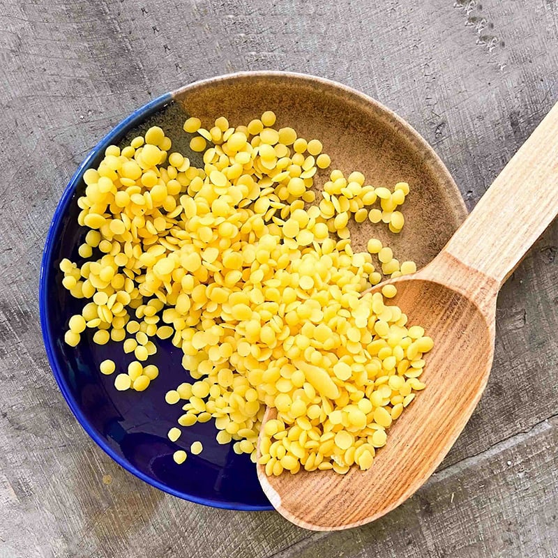 Beeswax Pastilles in wax dipped bowl with wooden spoon.