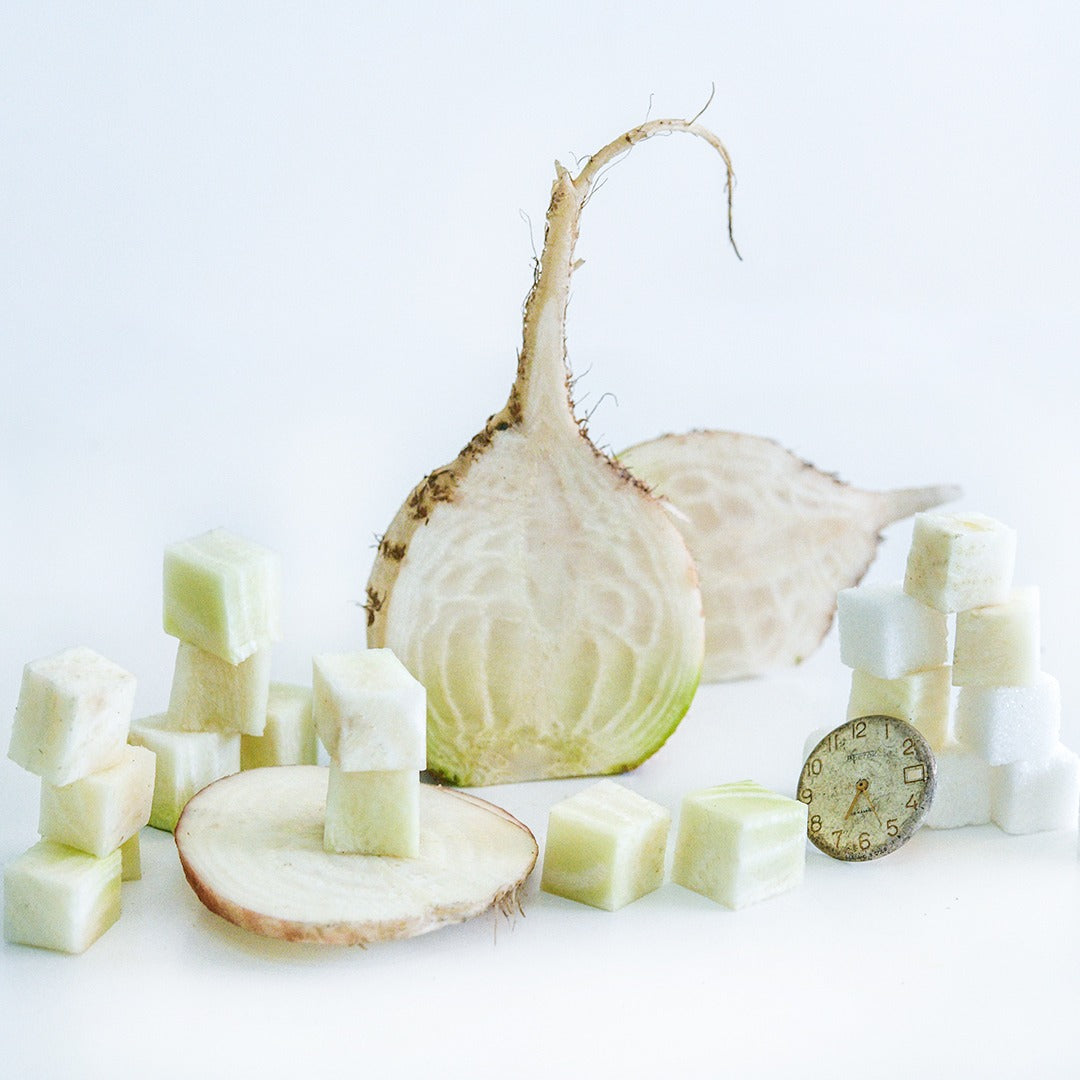 Halved and cut Albino Beets with sugar cubes and watch face on a white background.