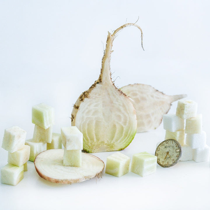Halved and cut Albino Beets with sugar cubes and watch face on a white background.