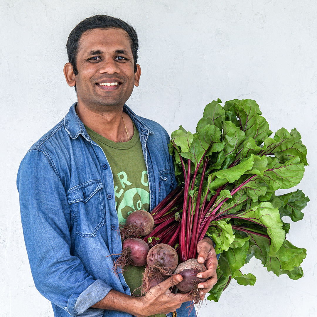A MESA intern from Sri Lanka smiles and holds a bunch of freshly harvested Crosby&