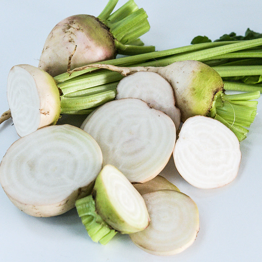Halved and whole Albino Beets arranged on white background.