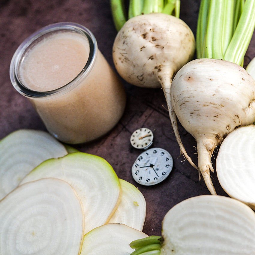 Albino Beets with slices and juice on a wooden cutting board.