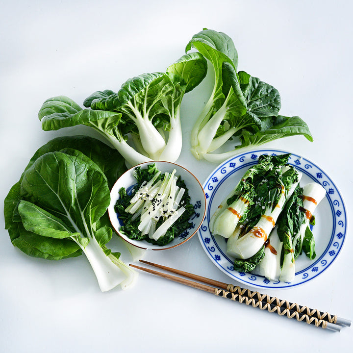 Fresh and cooked Baby Milk Bok Choy arranged on a white background.