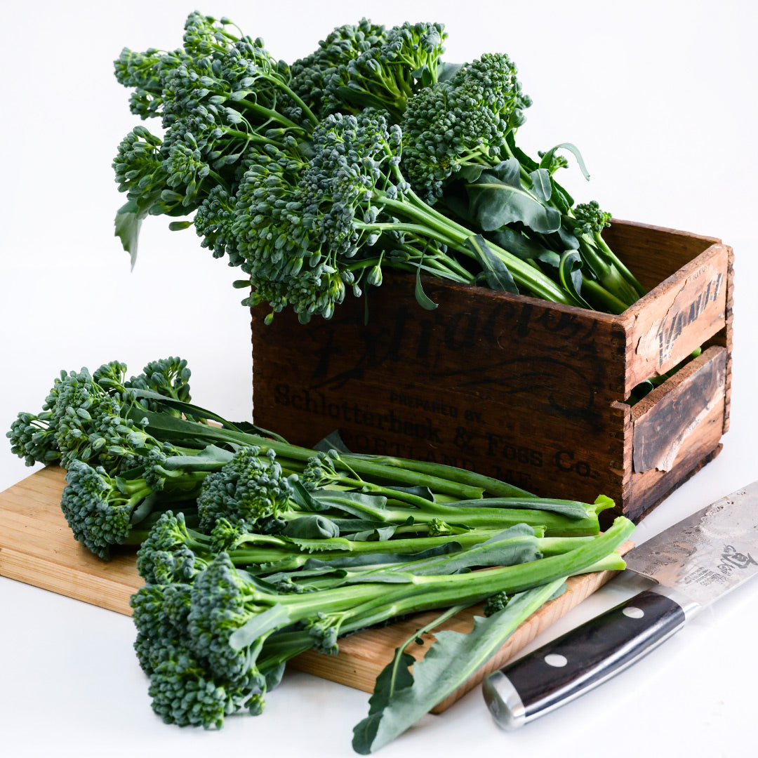 Waltham 29 Broccoli in a wooden box with a cutting board and knife on a white background.