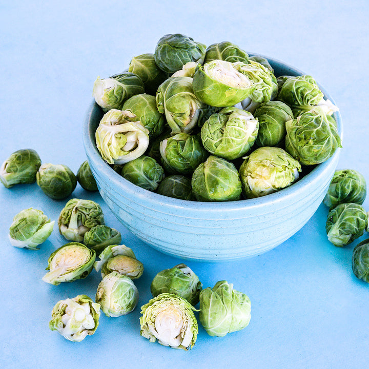 A blue bowl of Long Island Improved Brussels Sprouts on a light blue background.