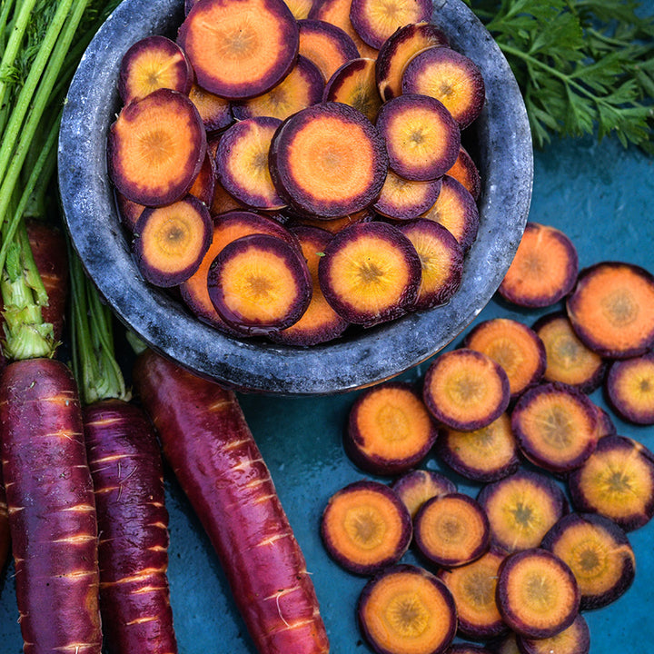 Close-up view of sliced Lila Lu Sang Carrots on a dark blue background.