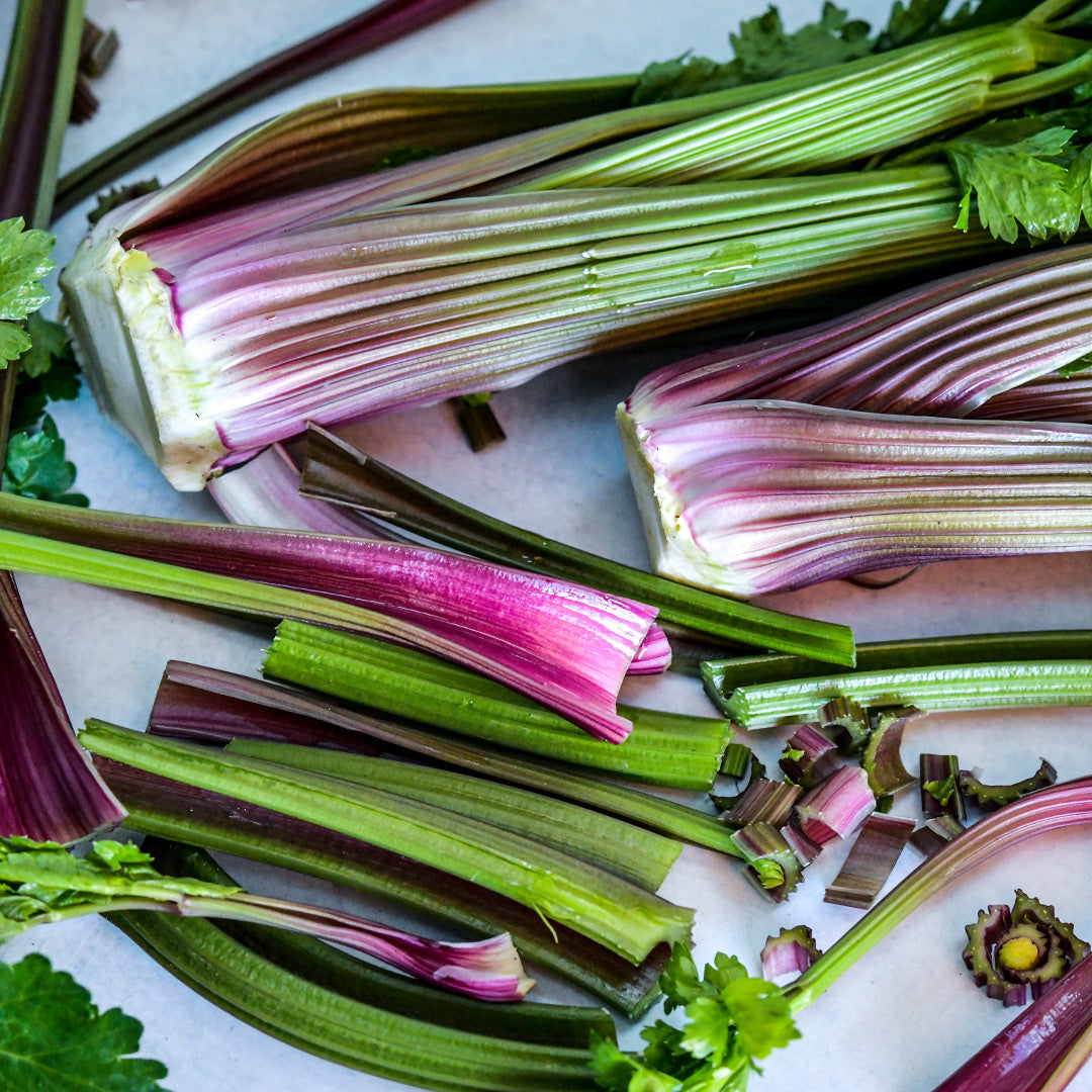 A close-up of cut and whole Giant Red Celery on a light background.