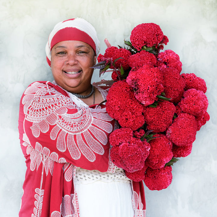 A Baker Creek employee smiles as she holds up a giant bouquet of Higyoku Red Stem Celosia blooms.