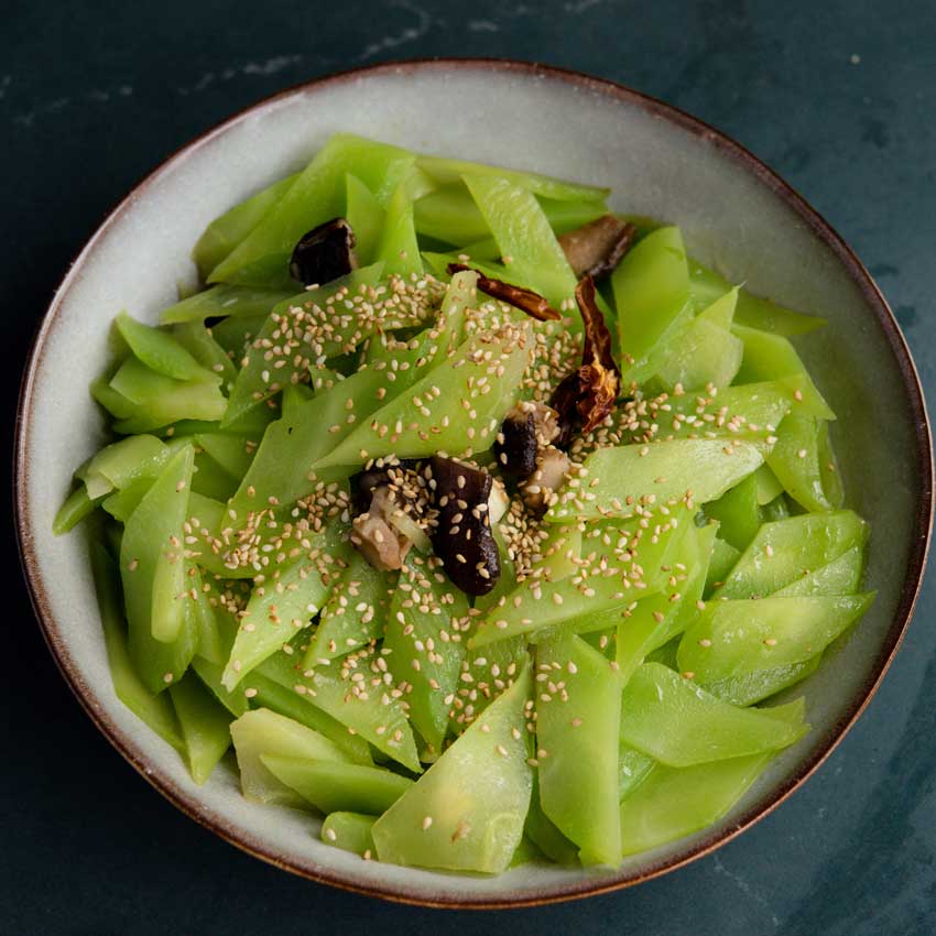 Green Mountain Celtuce Stirfry in a bowl on a dark blue background.