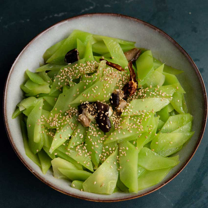 Green Mountain Celtuce Stirfry in a bowl on a dark blue background.
