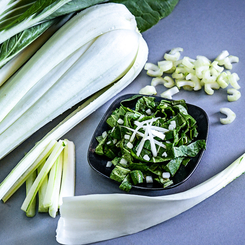 A close-up of a salad using greens from Snow White Bok Choy with thin sliced stems as topper.