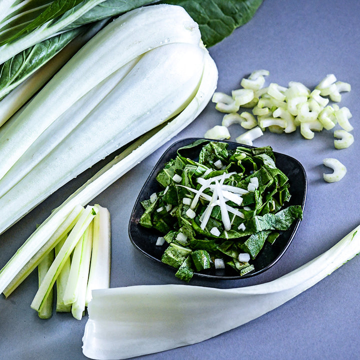 A close-up of a salad using greens from Snow White Bok Choy with thin sliced stems as topper.