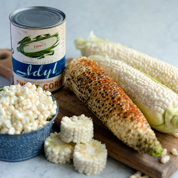 Cooked and raw Country Gentleman Sweet Corn cobs with extracted kernels and rounds.