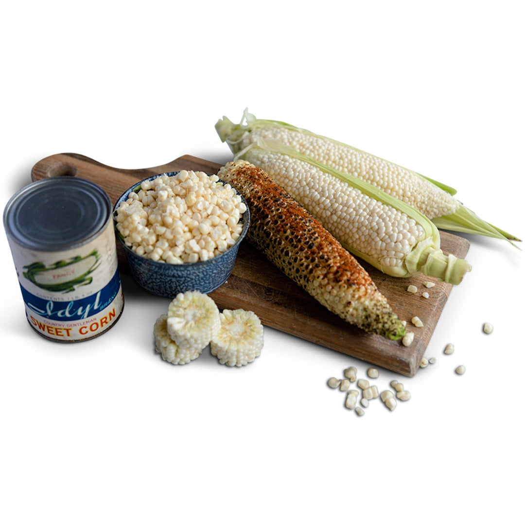 Country Gentleman Sweet Corn on a wood cutting board on a white background.