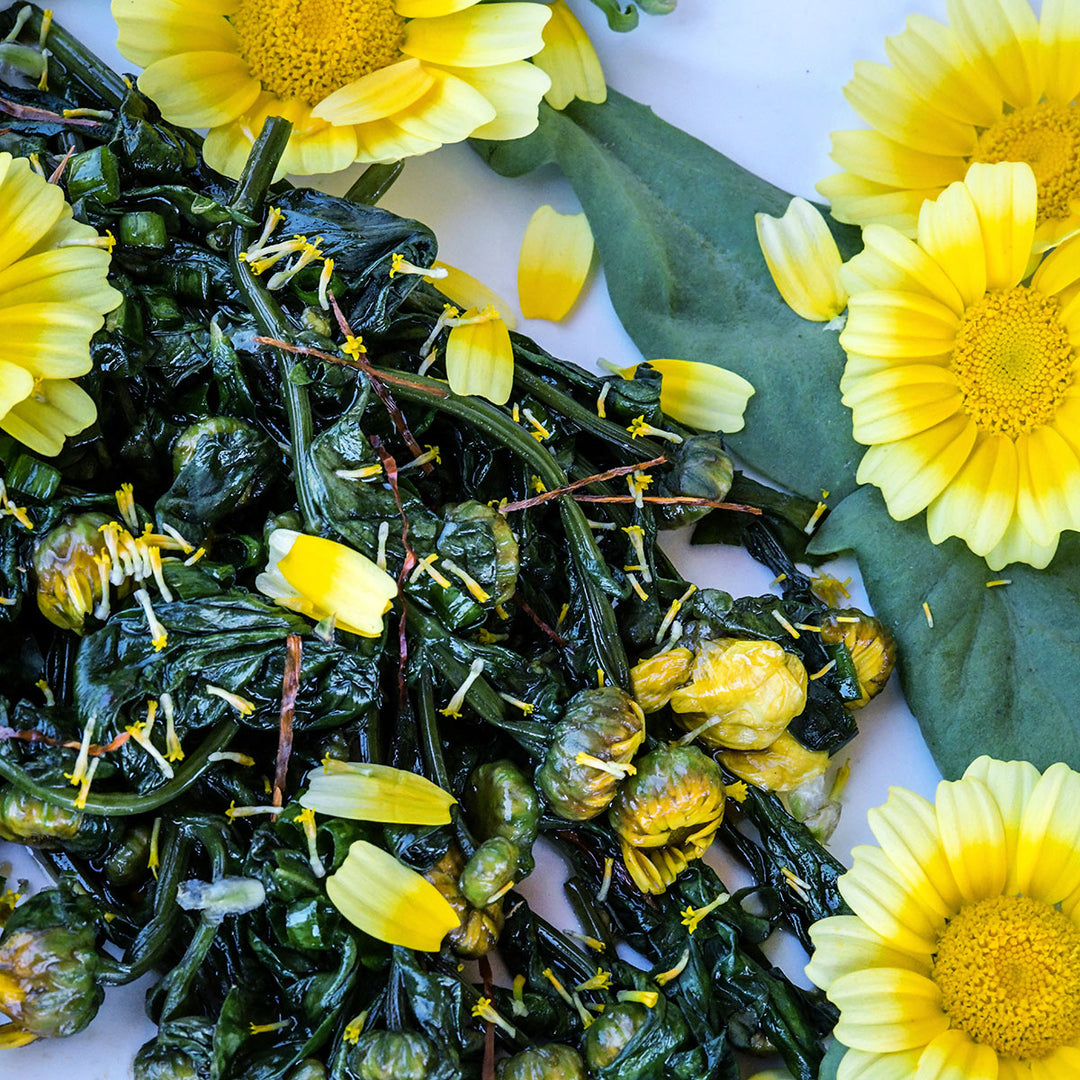 Big Leaf Tong Ho Chrysanthemum sauteed leaves with petal on white plate.