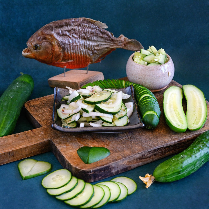Ancash Market Cucumber salad with sliced and whole cucumbers on a cutting board w a piranha.