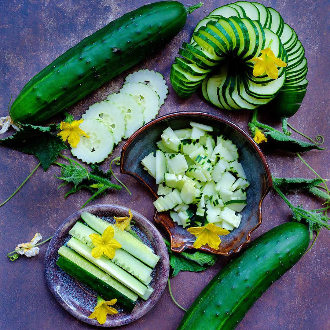 An overhead view of sliced, diced and whole Ancash Market Cucumbers arranged on a dark background.