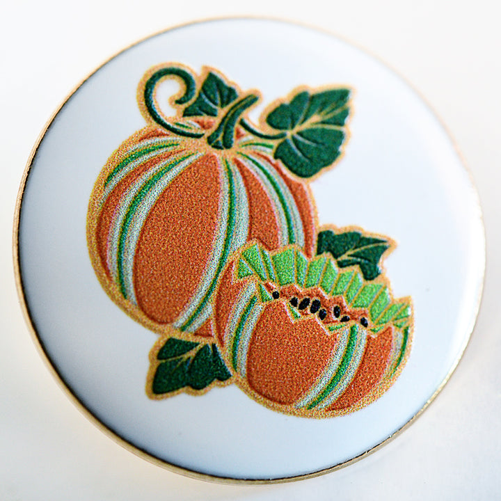 A close-up view of a Baker Creek Kajari Melon Limited Edition Pin on a light background.