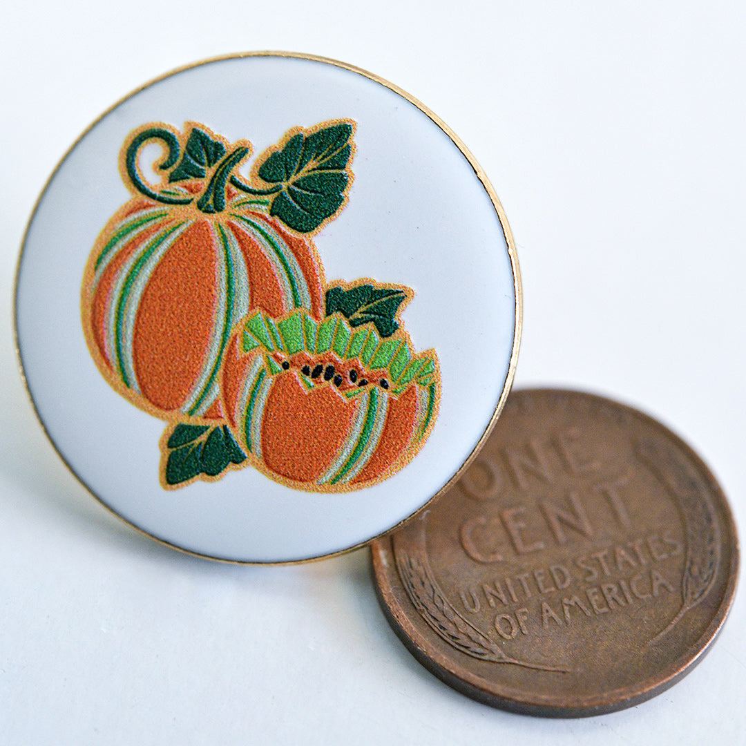 Baker Creek Kajari Melon Limited Edition Pin with a penny to show size on a white background.