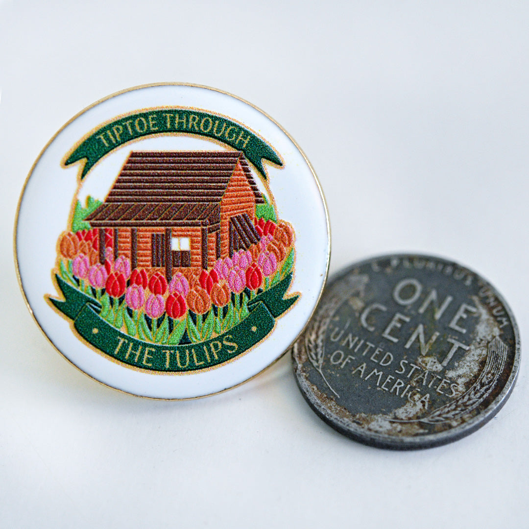 A Baker Creek Limited Edition Tulip Cabin Pin with a penny to show size.