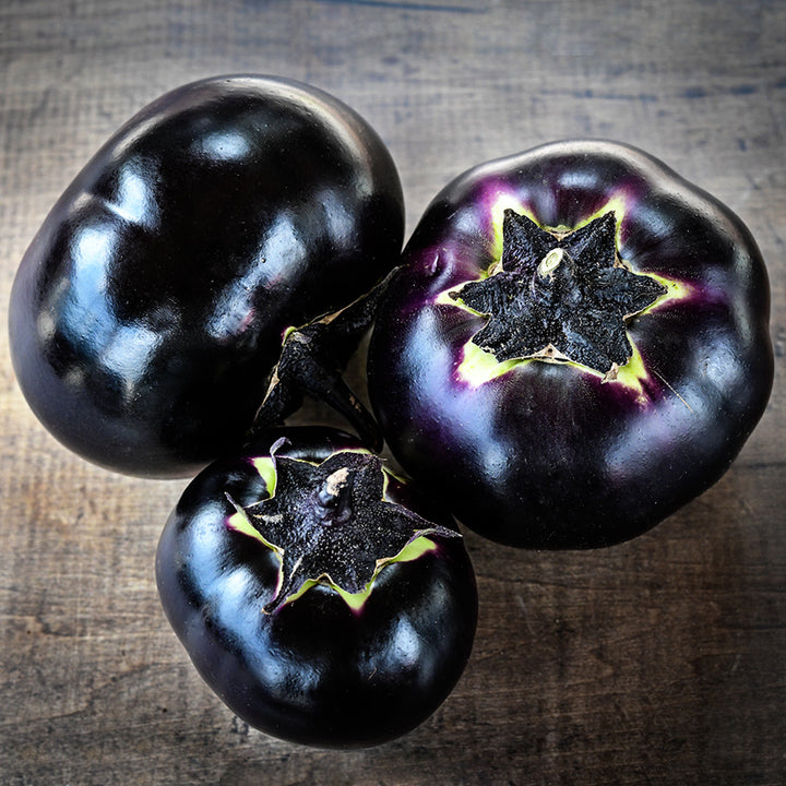 Three Qi Ye Round Eggplants on a wooden background.