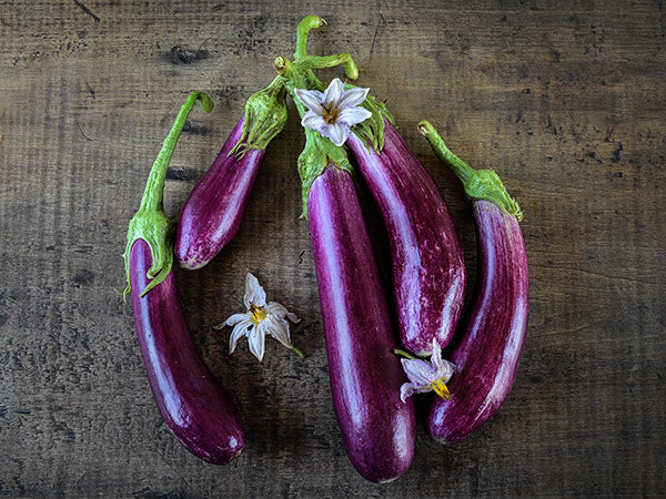 Neimat's Battir Eggplant with blooms on wooden background.
