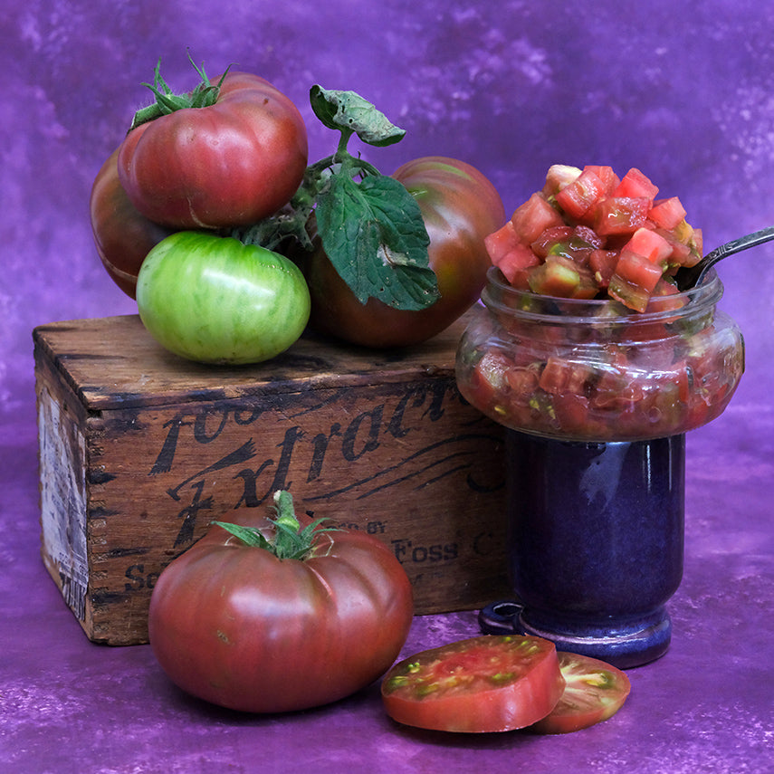 Purple Reign Tomatoes with chopped tomatoes in a jar on purple background.