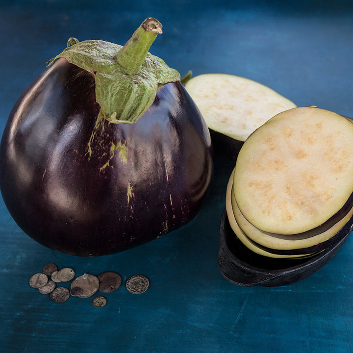 Aswad Eggplant with slices on blue background.