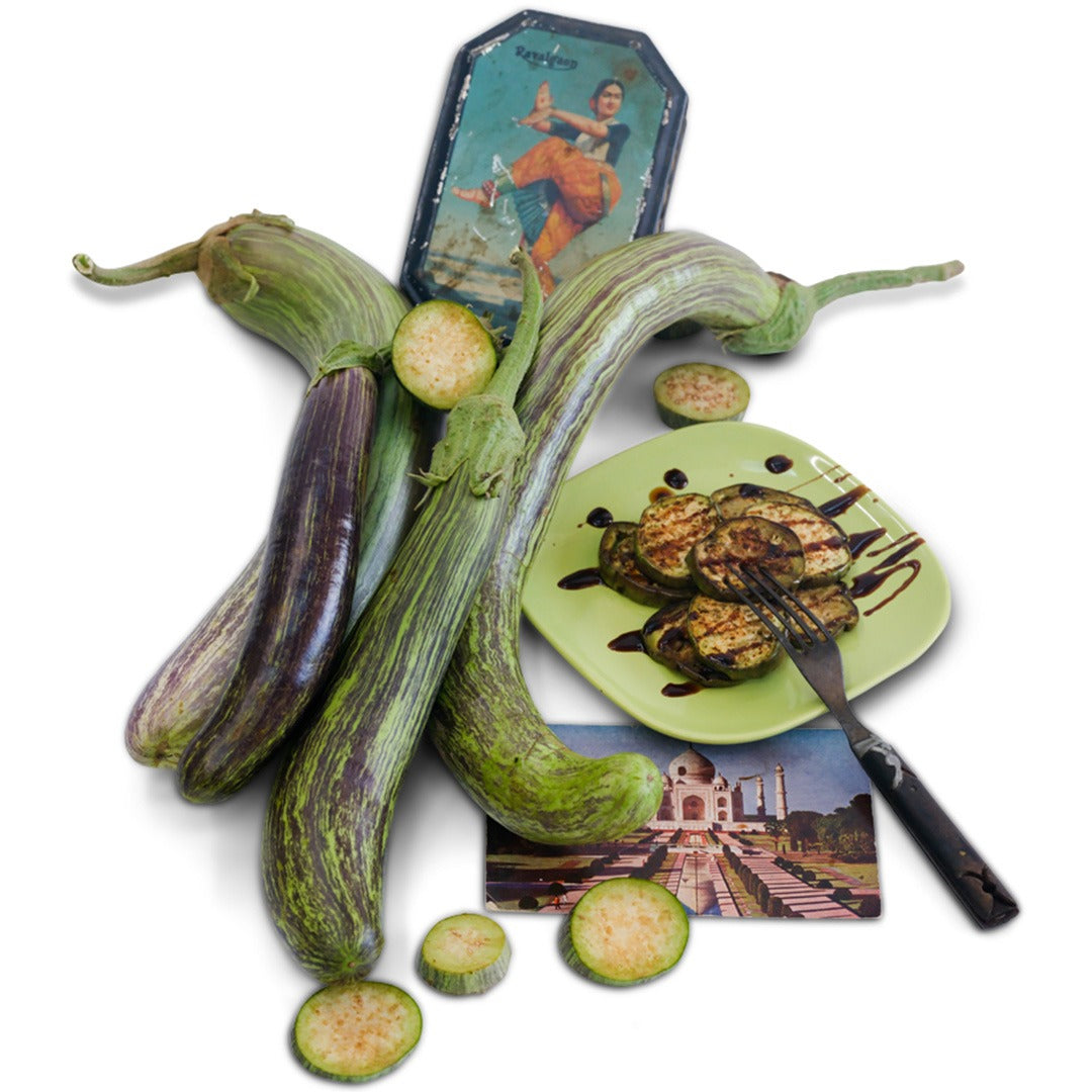 Niranjan Eggplants with grilled eggplant on a green plate with props from India on white.