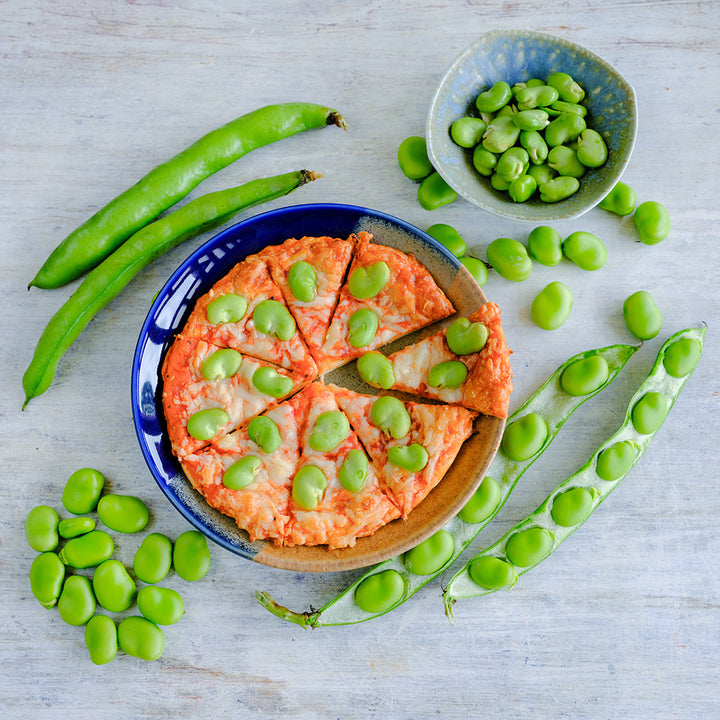 Masterpiece Fava Beans on a pizza and in bowl with raw beans and pods.