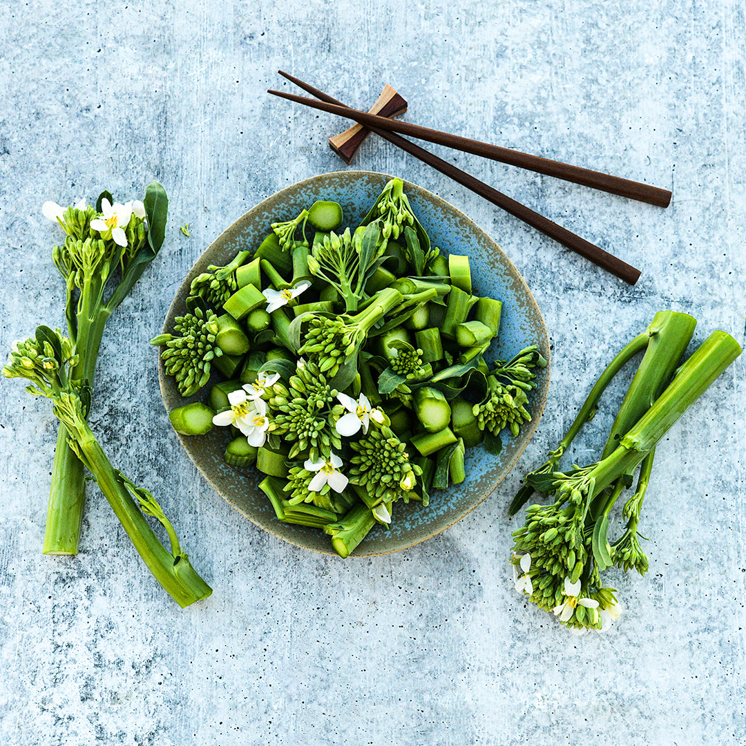 Chopped Yod Fah Chinese Broccoli greens and blooms in a ceramic bowl with chopsticks.