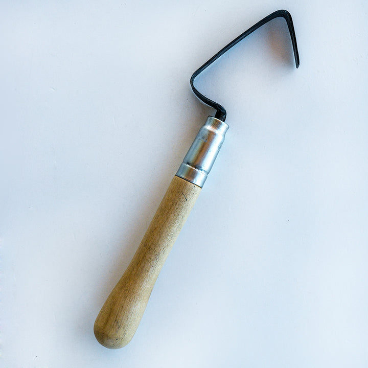 A hand-forged Haseltine Hand Weeder and Scraper sitting on a white background.