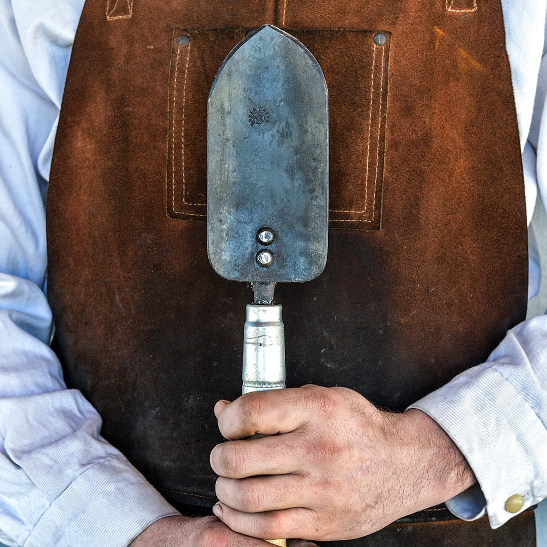 The Baker Creek blacksmith holding a Long Handled Trowel.