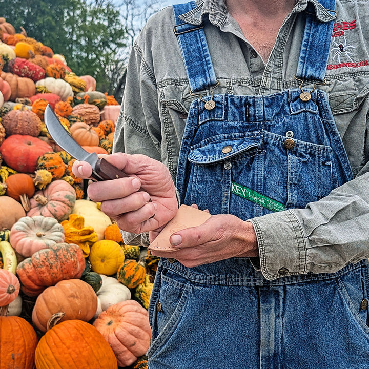 A closer view of Cody Hughes holding his handmade Ozarks Harvest Knife by pumpkins.