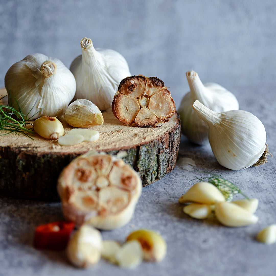 Roasted and raw Music Garlic on a light grey background.