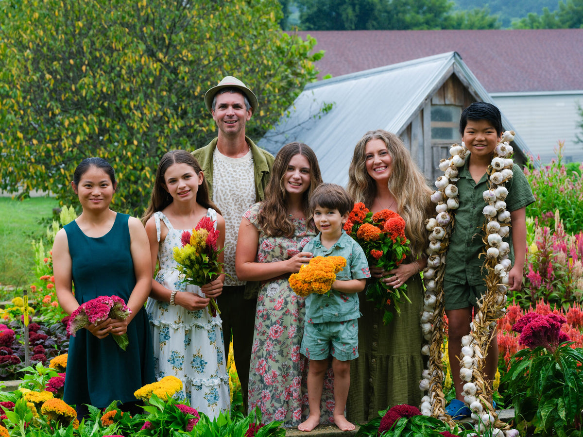 The Gettle family among celosia blooms in front of the greenhouse, holding bouquets and a braid of garlic