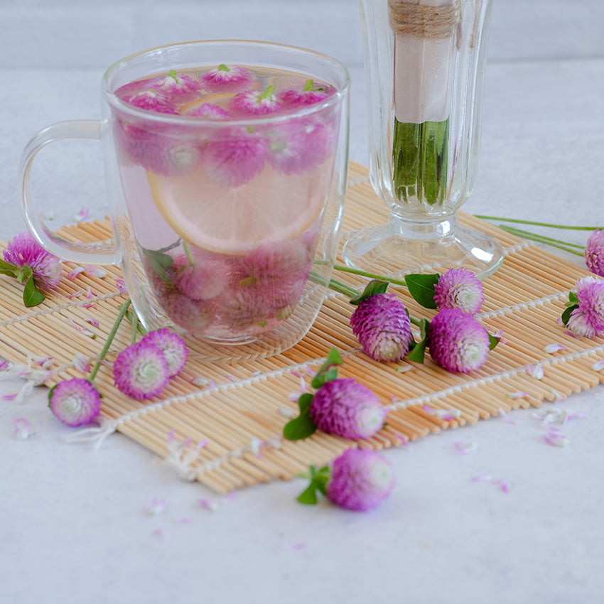 Atomic Purple Gomphrena tea with a loose blooms resting on a wooden mat.