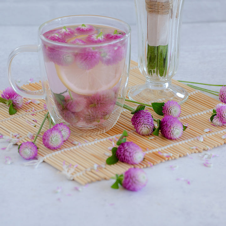 Atomic Purple Gomphrena tea with a loose blooms resting on a wooden mat.