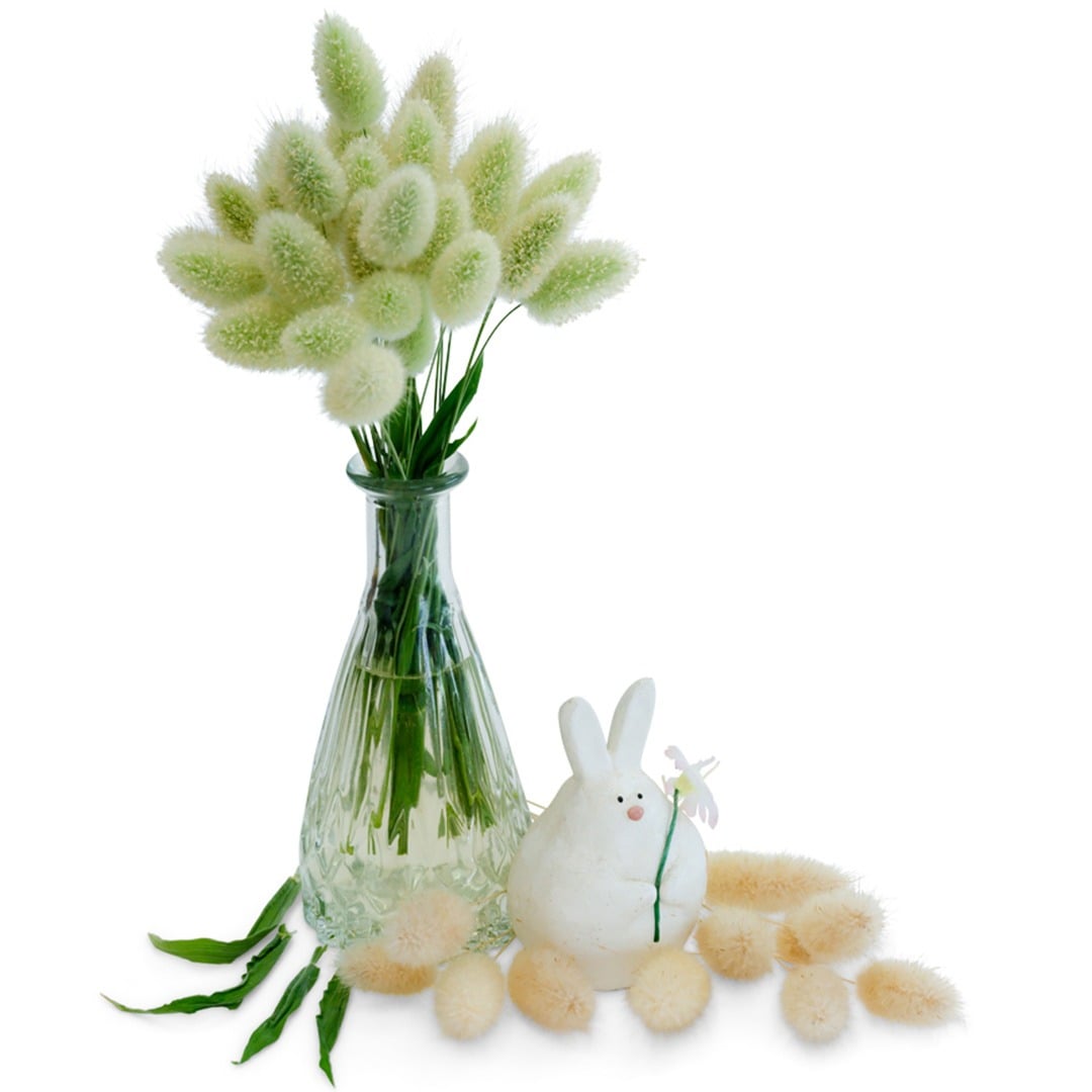 Bunny Tails grass in a glass jar with ceramic bunny statue on a white background