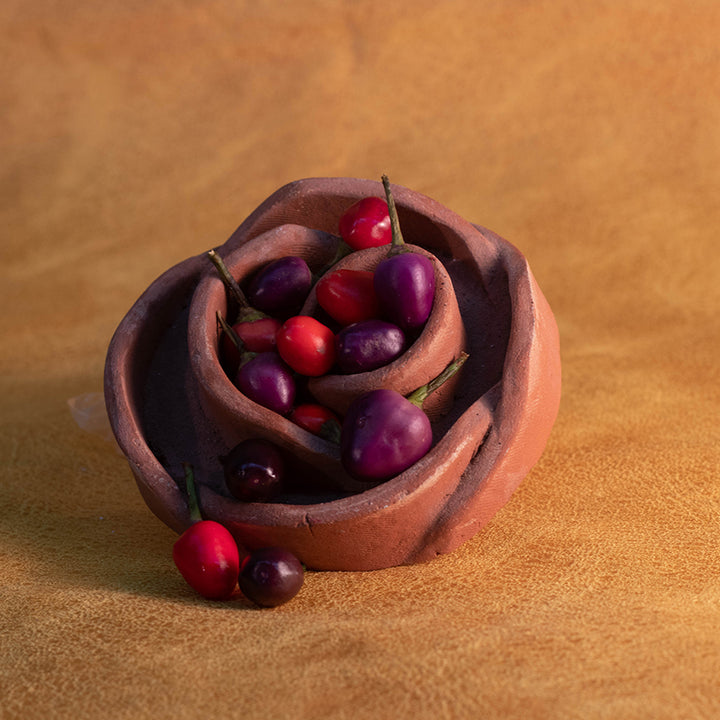 Filius Blue Peppers in decorative, flower shaped container on brown background.