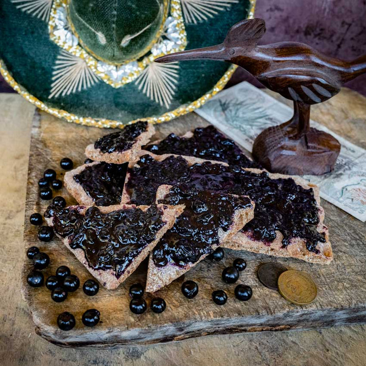 Chichiquelite Huckleberry jam with berries on triangle bread pieces with a sombrero in the background.