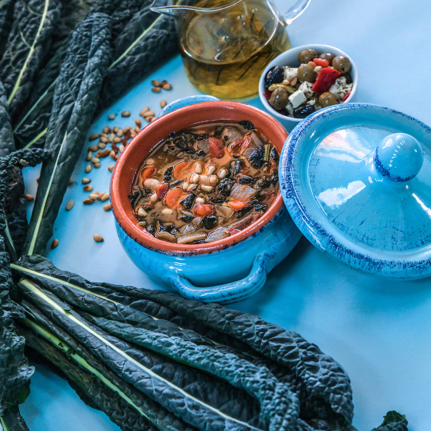 Nero di Toscana Kale soup with condiments on a blue background with fresh leaves.