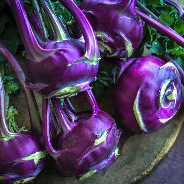 Close-up of a bouquet of Blauer Speck Kohlrabi on a wooden board.